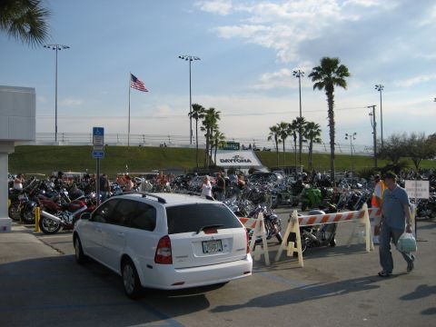1986 Ford Bronco - Daytona International Speedway parking lot filled with motorcycles and a white station wagon.