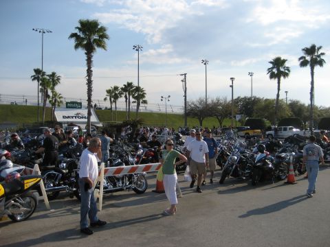 1986 Ford Bronco - A large gathering of motorcycles parked at Daytona, with palm trees and stadium lights visible in the background.
