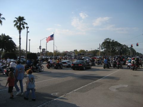 1986 Ford Bronco - A large gathering of motorcycles and cars under a bright sky with an American flag.