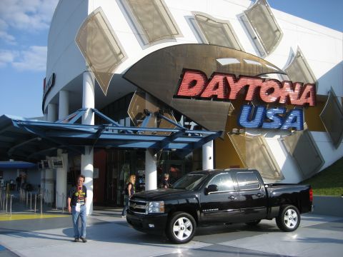 1986 Ford Bronco - A black Chevrolet Silverado pickup truck is parked outside the Daytona USA attraction.