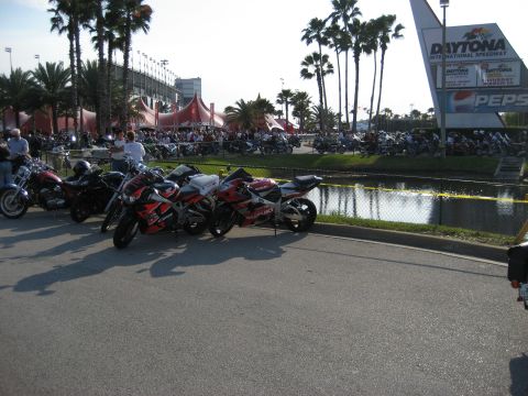1986 Ford Bronco - Motorcycles are parked in front of the Daytona International Speedway grandstands and tents.