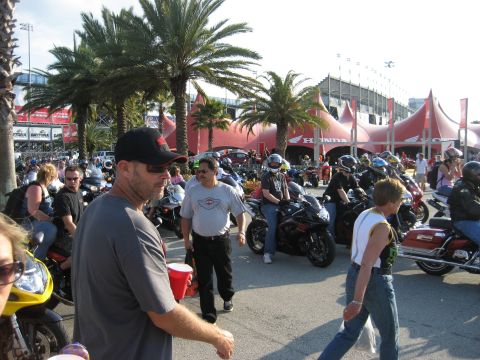 1986 Ford Bronco - Outdoor gathering with numerous motorcycles and attendees, palm trees and a large tent structure.