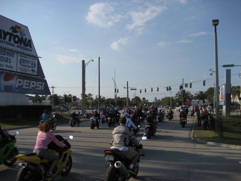 1986 Ford Bronco - A large group of motorcycles are gathered on a sunny day near the Daytona International Speedway.