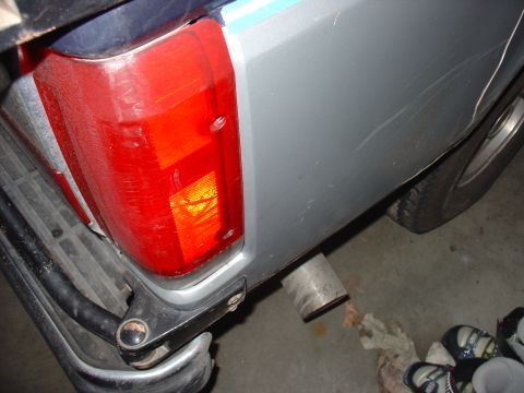 1988 Ford Bronco - Close-up of the rear quarter panel and taillight assembly of a silver SUV, showing the exhaust pipe and tire.