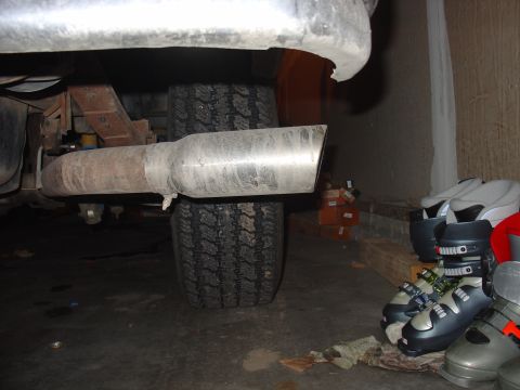 1988 Ford Bronco - Close-up view of a vehicle's exhaust pipe and tire, with ski boots visible in the background.