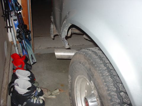 1988 Ford Bronco - Damage to the rear wheel well of a silver vehicle, with an exhaust pipe visible.