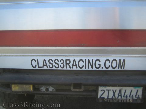 1990 Ford Bronco - Close-up of a white vehicle's lower tailgate showing a red stripe, CLASS3RACING.COM lettering and a California license plate reading 2TXA44…