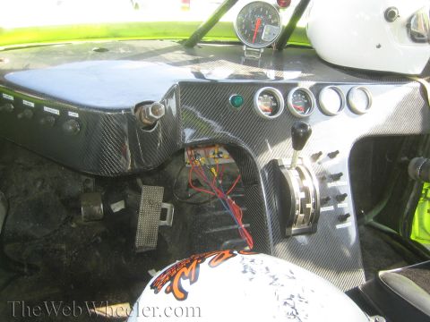 1990 Ford Bronco - Interior of an off-road race truck showing a carbon-fiber dashboard with round gauges, a center shifter and exposed wiring.