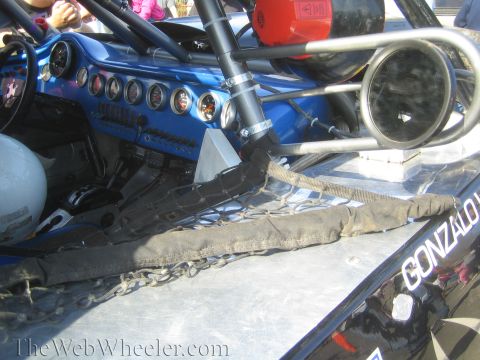 1990 Ford Bronco - Interior detail of a blue off-road race truck showing a gauge panel, roll cage tubing, chains and the name GONZALO on the body.