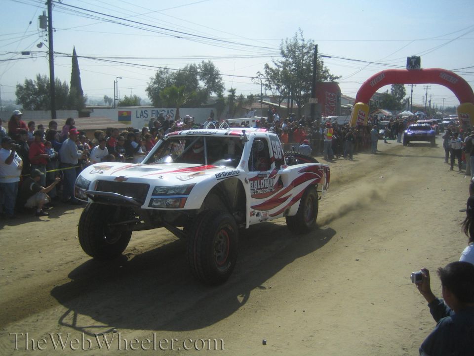 White and red Baldwin Motorsports off-road trophy truck on dirt course