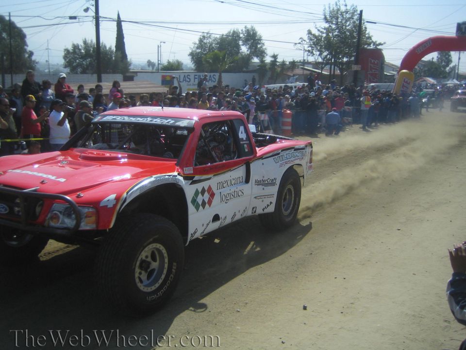 Red and white Mexicana Logistics off-road trophy truck on dirt course