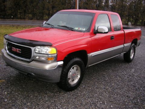 1994 Ford Probe - A red and silver GMC pickup truck is parked on a gravel surface with trees in the background.