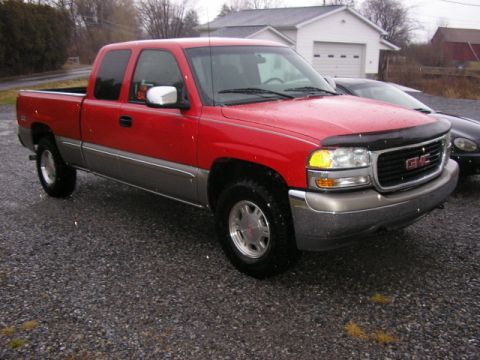 1994 Ford Probe - Red GMC Sierra pickup truck with a two-tone gray lower body is parked on a gravel lot.