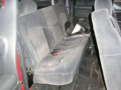 1994 Ford Probe - The interior of a vehicle shows a gray bench seat with seatbelts and a black object on the seat.