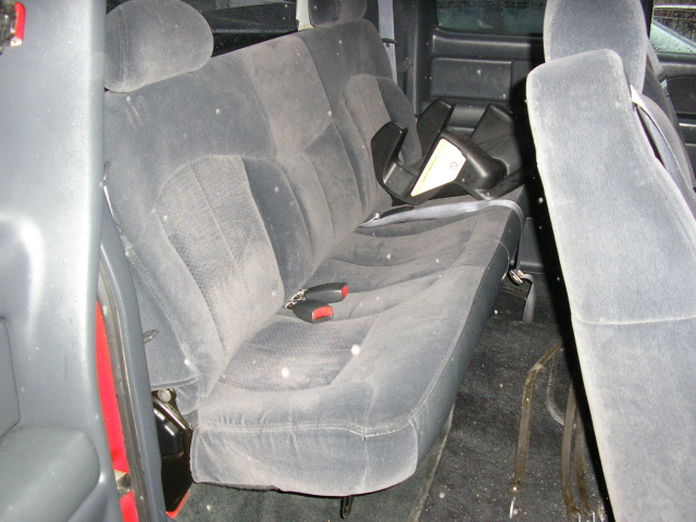 Back seat and floor of a vehicle, with a black plastic item on the seat