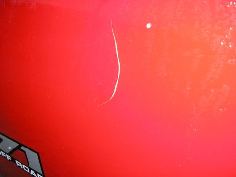 1994 Ford Probe - A close-up of a red vehicle's body shows a scratch and part of an "OFF ROAD" graphic.
