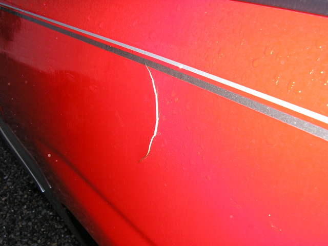 Red 1994 Ford Probe side panel with a paint crack and silver trim