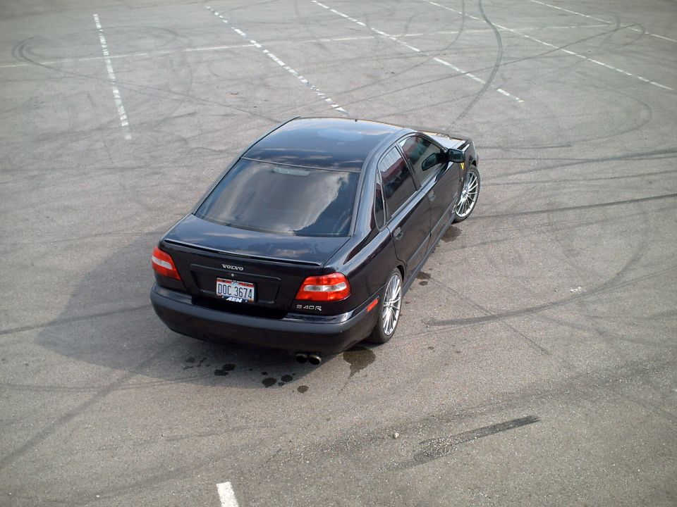 Elevated rear view of dark Volvo sedan on skid-marked asphalt lot