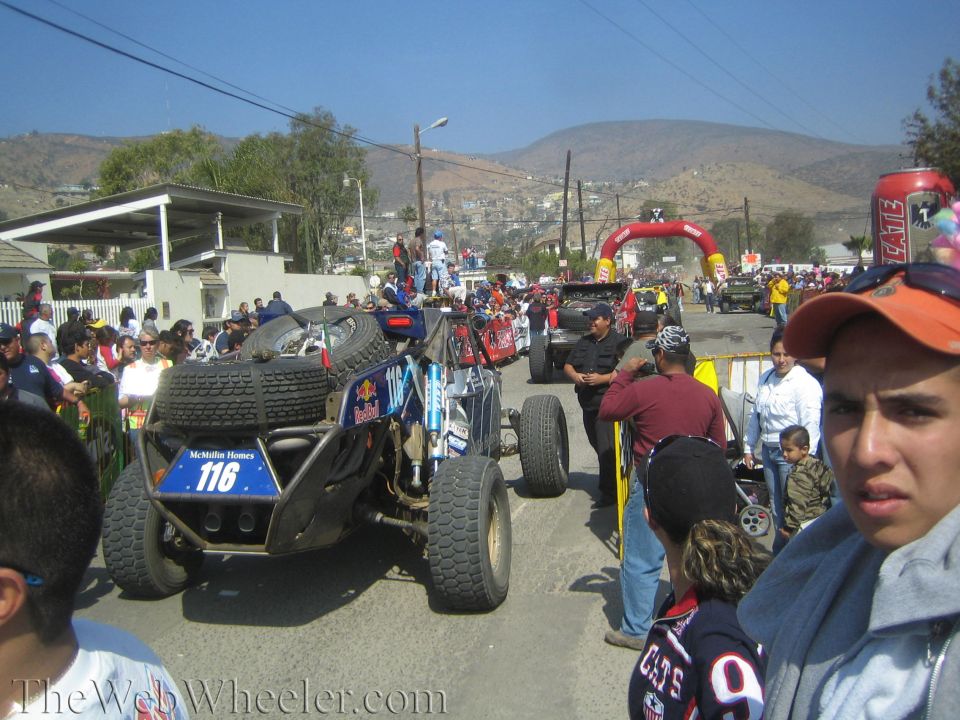 No. 116 off-road buggy on a street with red start arch and hillside town behind