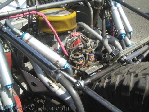 1990 Ford Bronco - Close-up of an off-road buggy engine bay showing a yellow air cleaner, carburetor, headers and tube-frame shocks.