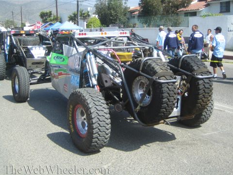 1990 Ford Bronco - Rear view of a tube-frame off-road buggy with twin mounted spare tires and a mid-engine layout on a staging street.