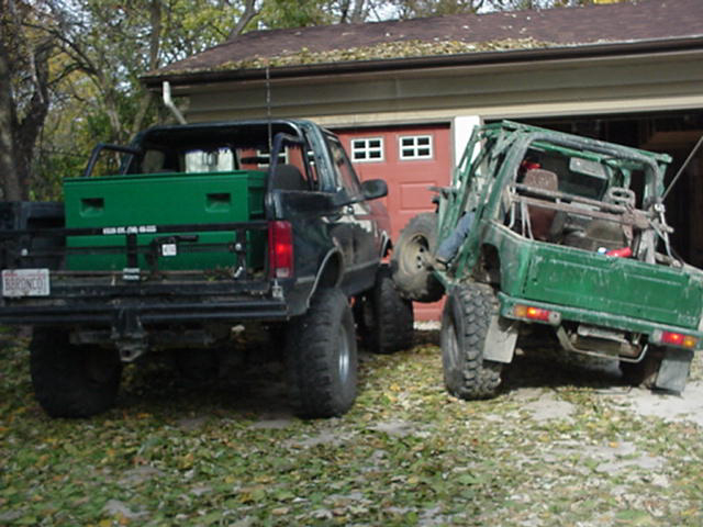black pickup truck with green toolbox next to a green off-road vehicle
