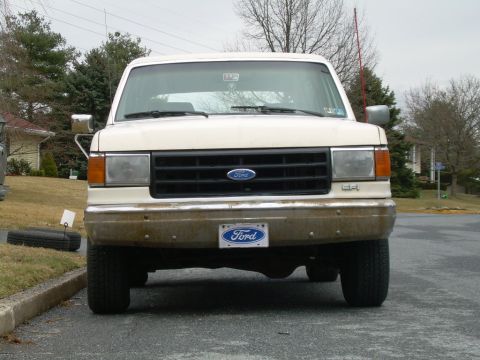 1988 Ford Bronco - A white Ford truck is parked on a street with trees and houses in the background.
