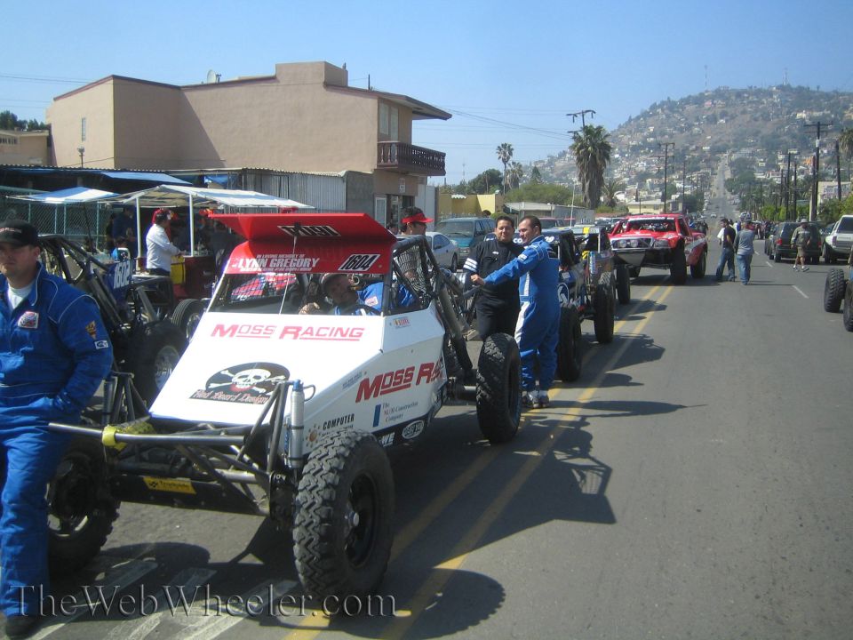 Open-wheel off-road buggies and prerunners staged along a street