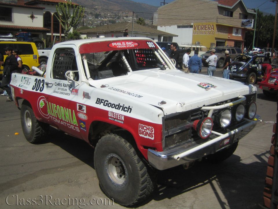White and red Ford off-road race truck #303 with auxiliary lights