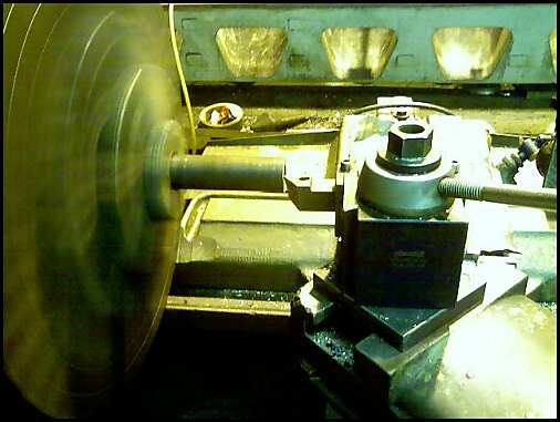 Metalworking lathe with a large spinning disc on the left and a tool holder on the right