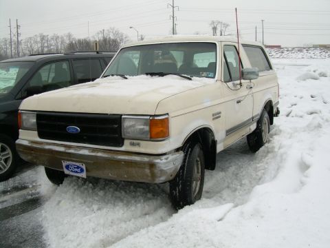 1988 Ford Bronco - A Ford Bronco is stuck in the snow, with a dark SUV parked nearby.