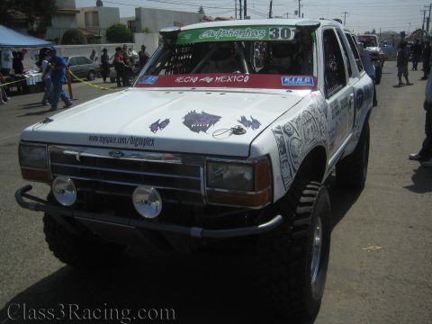 1990 Ford Bronco - Front view of a lifted white Ford SUV race truck numbered 30 with Hecho en Mexico graphics and twin front light pods.