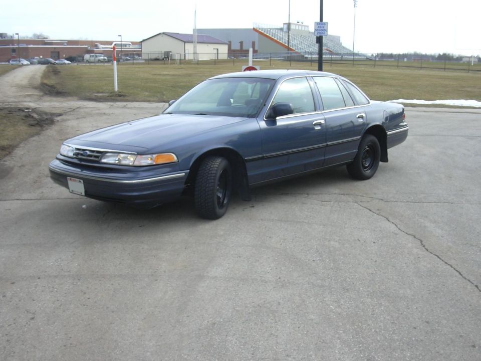 Blue sedan parked on asphalt, front quarter view. Black wheels, some snow on the ground