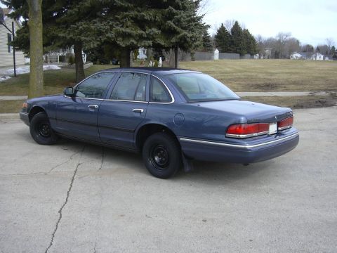 1996 Ford Crown Victoria - Rear 3/4 view of a blue 1995 Ford Crown Victoria sedan parked on a cracked concrete driveway.