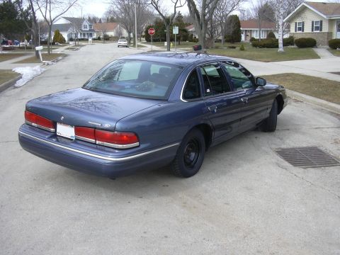 1996 Ford Crown Victoria - The rear of a blue sedan is shown parked on a residential street. The vehicle appears to be from the early to mid-1990s.
