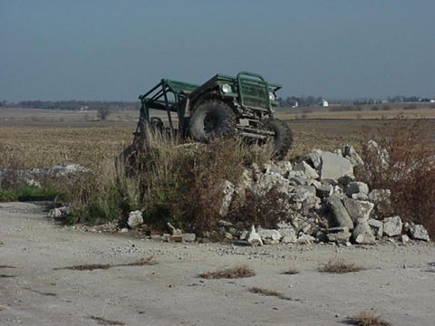 1992 Ford Bronco - An off-road vehicle sits atop a pile of rubble in a field.