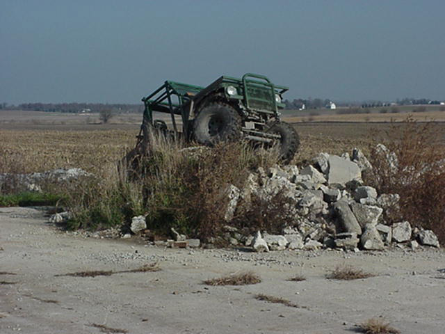 Green off-road vehicle with roll cage on a pile of rubble