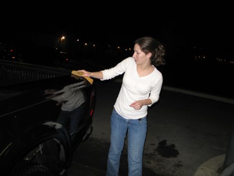 2003 Ford Ranger - A woman washes the side of a black 2003 Ford Ranger pickup truck at night.