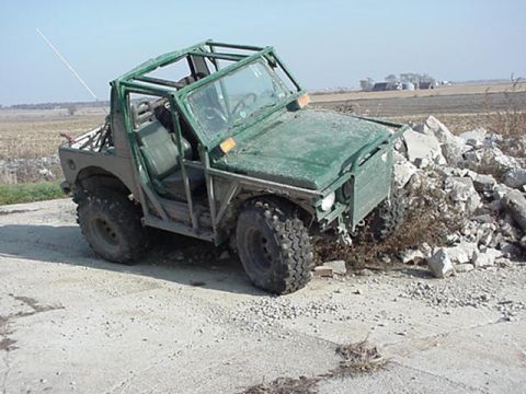 1992 Ford Bronco - This green off-road vehicle appears to be modified for extreme terrain, with a prominent roll cage and oversized tires.