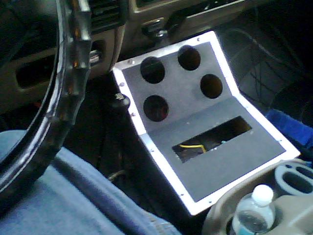 Custom center console with four circular cutouts and a rectangular opening, showing wiring. Steering wheel and part of dashboard visible