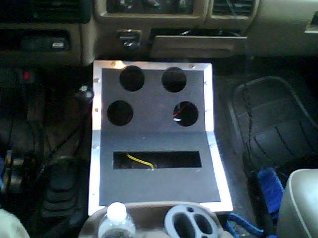 Custom center console with four cup holders and a rectangular cutout, installed in a vehicle interior. Wires are visible in the cutout