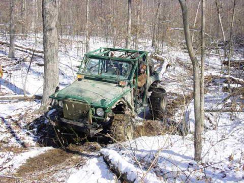 1992 Ford Bronco - An off-road vehicle is stuck in a snowy, wooded area.