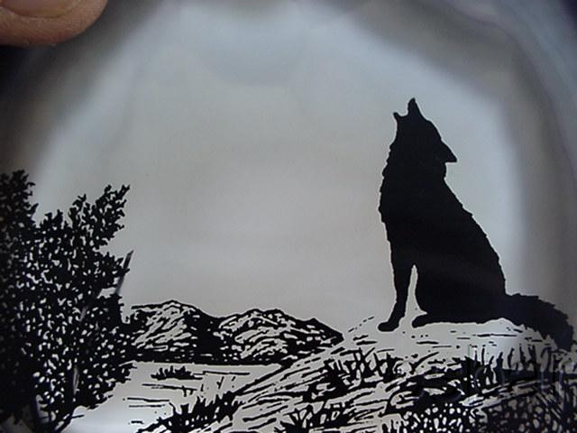 Silhouette of a howling wolf on a rocky hill with mountains and trees, watermarked "SUPERMOTORS.NET"