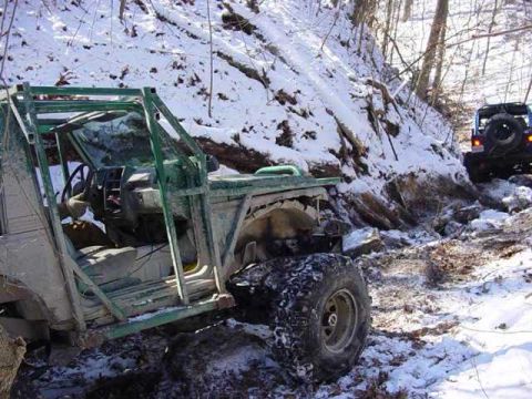 1992 Ford Bronco - Two off-road vehicles navigate a snowy, wooded trail.
