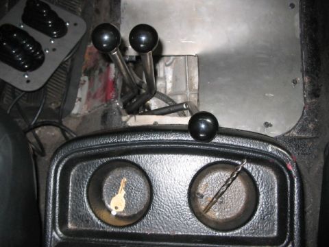 1991 Ford Bronco - The vehicle's interior features a complex shifter setup and two cup holders, one with a key and the other with a drill bit.