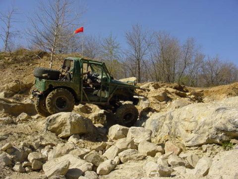 1992 Ford Bronco - This off-road vehicle navigates a rocky terrain under a clear blue sky.
