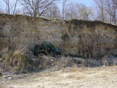 1992 Ford Bronco - An off-road vehicle is positioned on a rocky incline with a cliff face in the background.