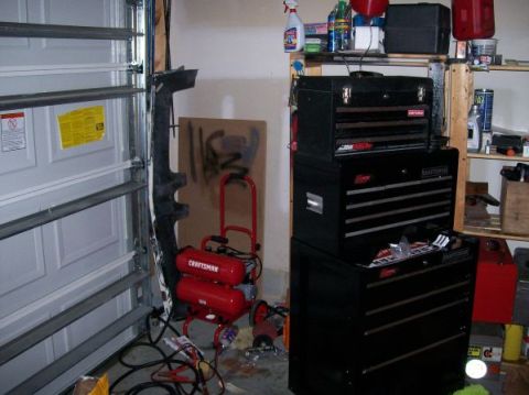 1996 Ford Bronco - A garage scene a red Craftsman air compressor and stacked toolboxes next to a closed garage door.