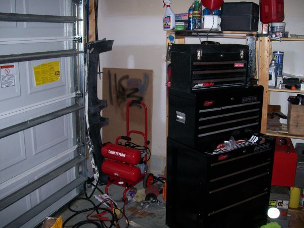 Garage scene with red Craftsman air compressor, toolboxes, and a garage door