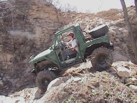 1992 Ford Bronco - A driver navigates a challenging off-road trail in a , green vehicle.